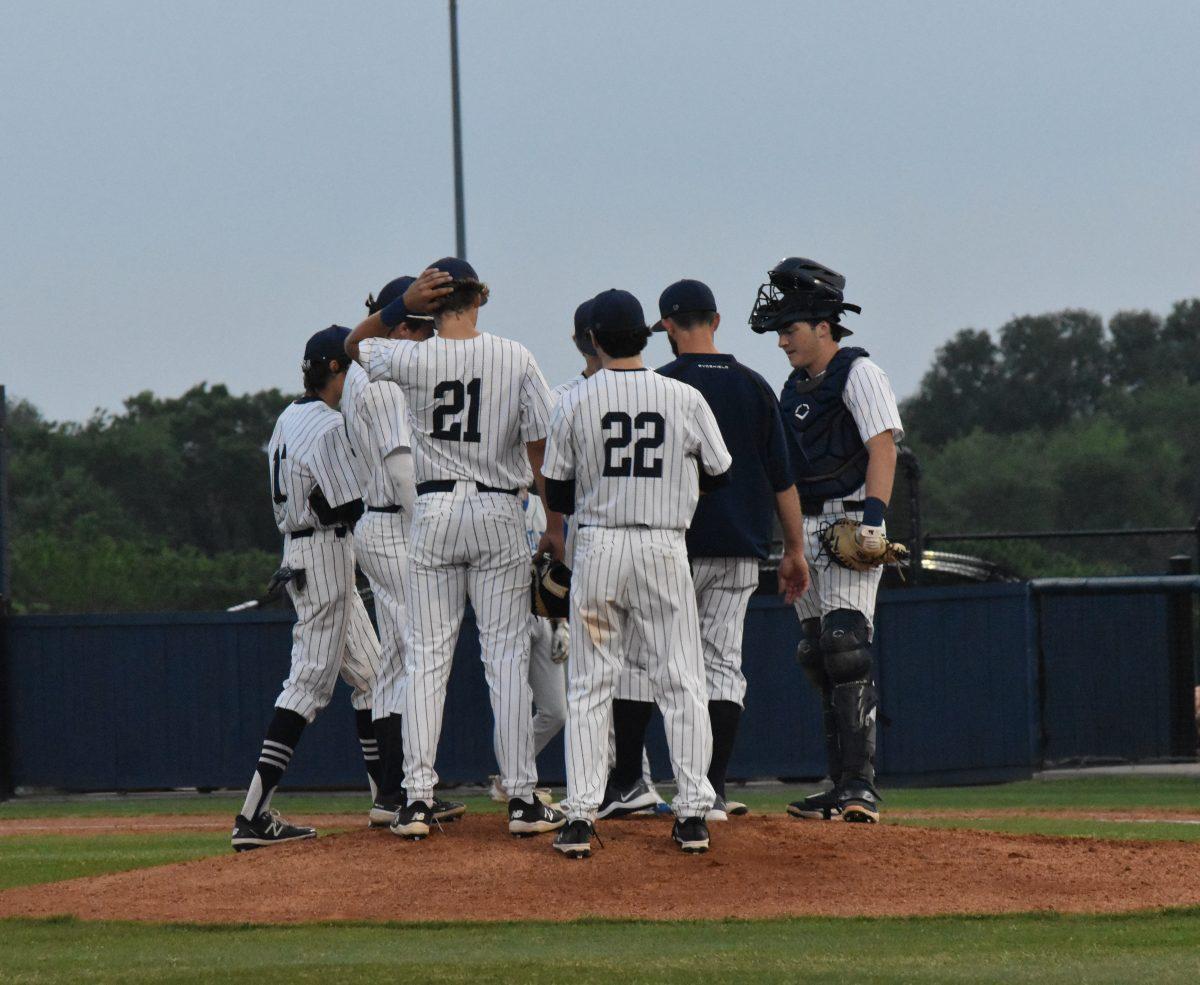 The Varsity Baseball Team meets on the pitcher mound for a mid-game strategy review