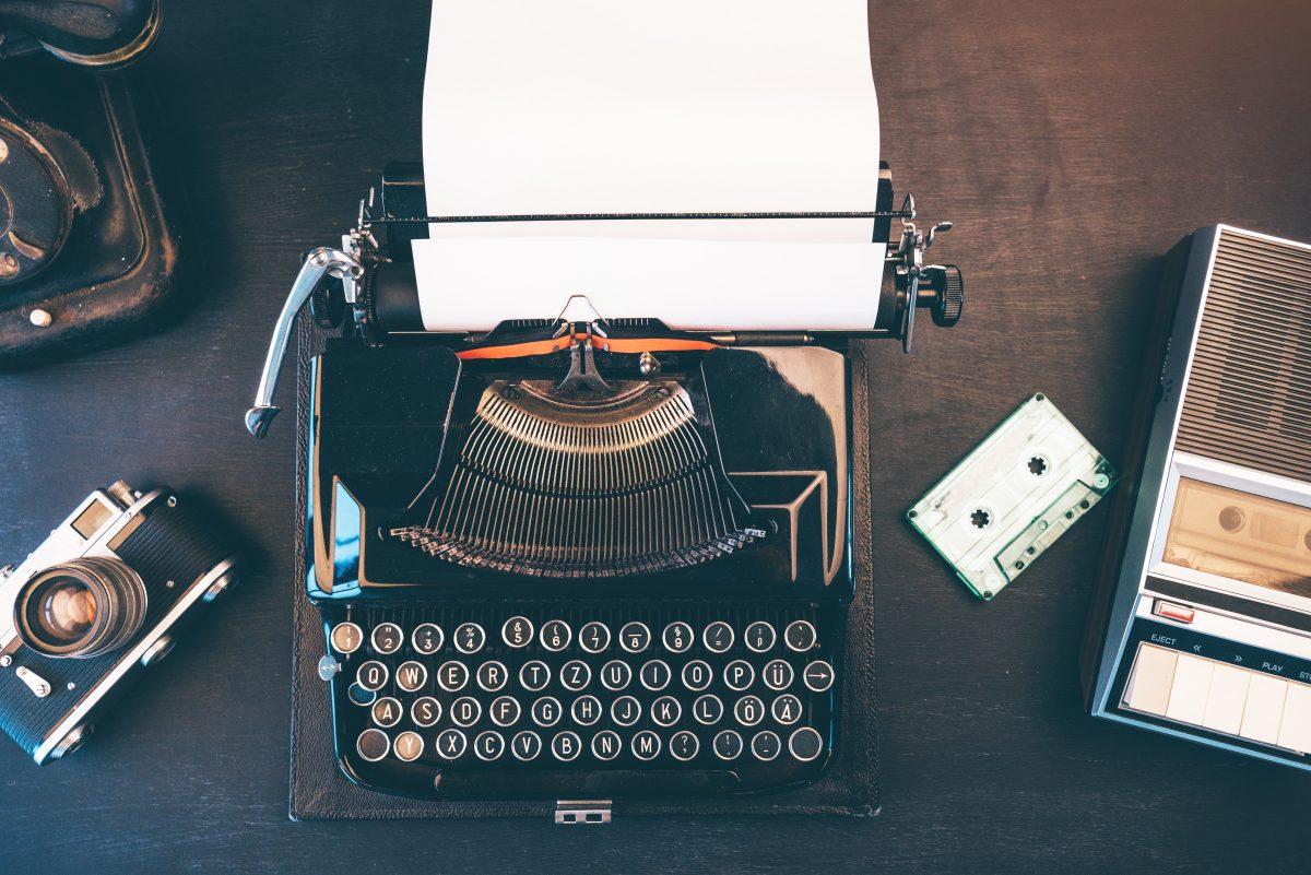 Top view of vintage journalist workspace with telephone, typewriter and audio cassette tape player