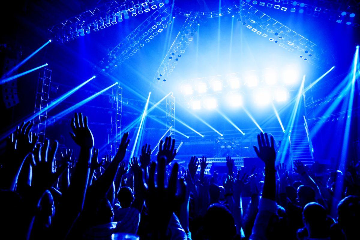 Rock concert, crowd of young people enjoying night performance, raised up and clapping hands, dance club, bright blue lights, music entertainment